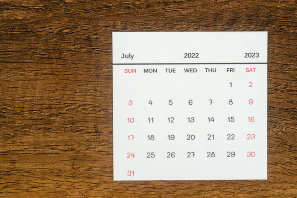 Top uitzicht Kalender bureau Juli is de maand voor organisatoren om te plannen en te herinneren op de houten tafel achtergrond. - Foto, afbeelding