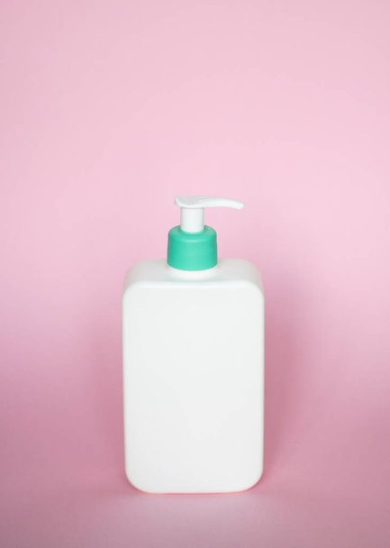 Large white plastic bottle with pump dispenser as a liquid container for gel, lotion, cream, shampoo, bath foam on pink background - Foto, Bild
