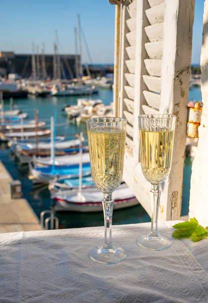 Birthday celebration in summer with two glasses of French champagne sparkling wine and view on colorful fisherman's boats in old harbour in Cassis, Provence, France - Foto, Imagem