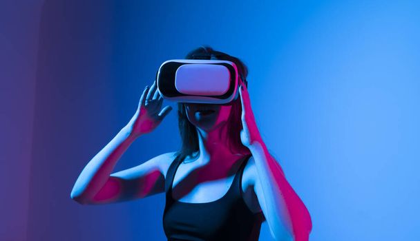 Happy brunette girl getting experience using VR headset glasses of virtual reality and exploring a new virtual world without bounds - Photo, Image