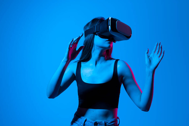 Young woman working in VR goggles on a grey background. Modern architect using virtual reality glasses at workplace. Designer working in augmented reality vr studio - Foto, Bild