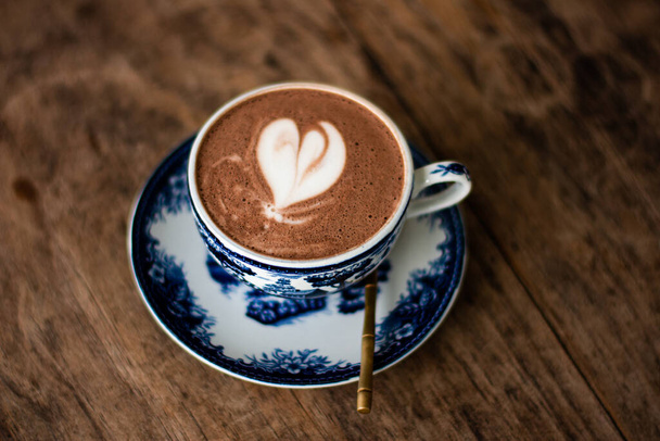 Hot chocolate with heart shape on the table brown wood. - Fotoğraf, Görsel