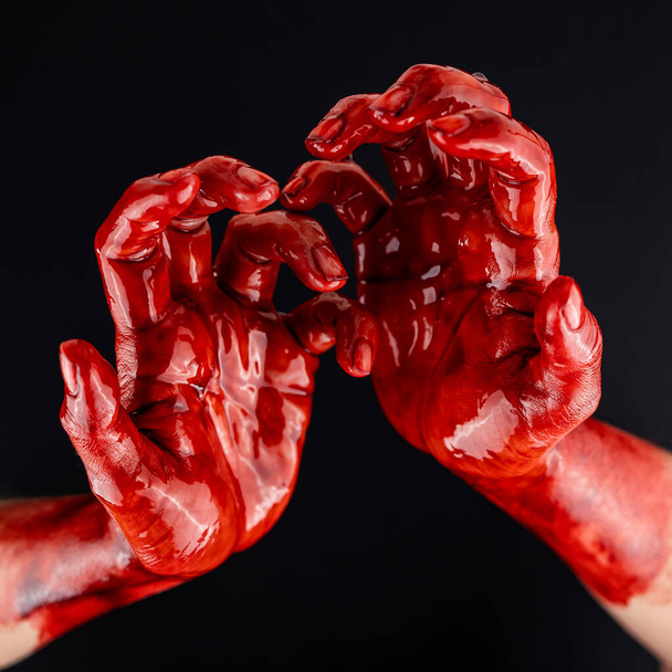 Womens hands in blood on a black background - Foto, afbeelding