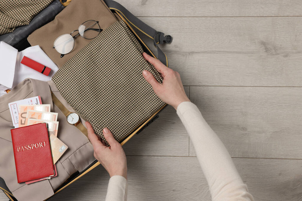 Woman packing suitcase on wooden floor, top view with space for text. Business trip planning - Foto, Imagem