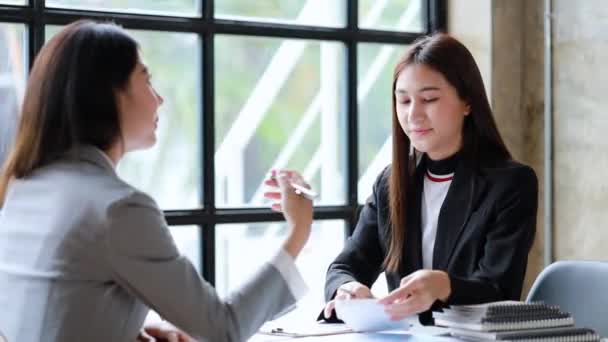 Két gyönyörű ázsiai nő találkozik egy céges tárgyalóban, hogy megvitassák az üzleti terv fejlesztésére és az üzleti terv követésére irányuló terveket. Üzleti megbeszélés ötlete. - Felvétel, videó