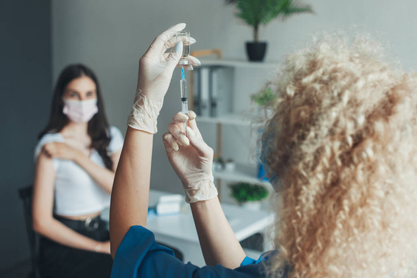 Enfermera en guantes blancos sosteniendo, covid-19 enfermedad de la vacuna preparándose para el ser humano. Médico que prepara una dosis para un paciente de la tercera vacuna de Covid-19 - Foto, Imagen