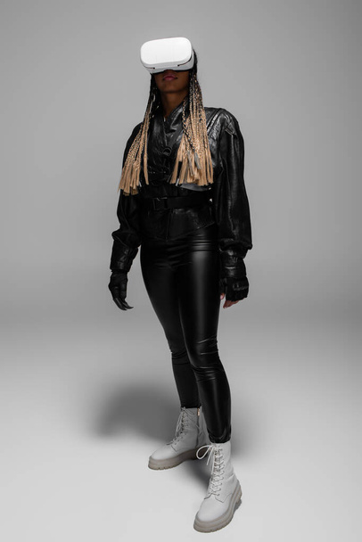 Full length of african american woman gaming in vr headset on grey background  - Foto, Imagem