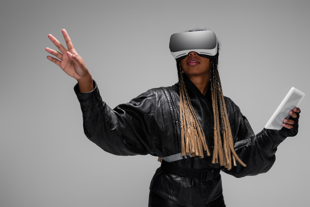 Stylowa, afrykańska kobieta w wirtualnej rzeczywistości z cyfrowym tabletem odizolowanym na szaro  - Zdjęcie, obraz