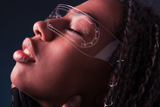 Vista laterale della donna afroamericana in occhiali intelligenti isolati su grigio scuro  - Foto, immagini