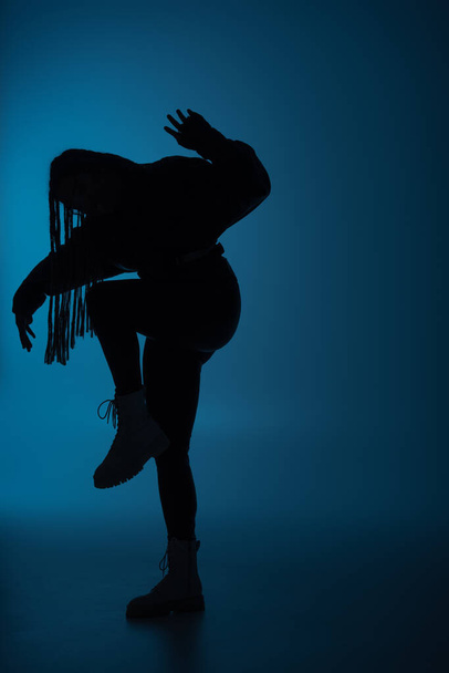 Silueta de mujer afroamericana moviéndose sobre fondo azul oscuro  - Foto, Imagen