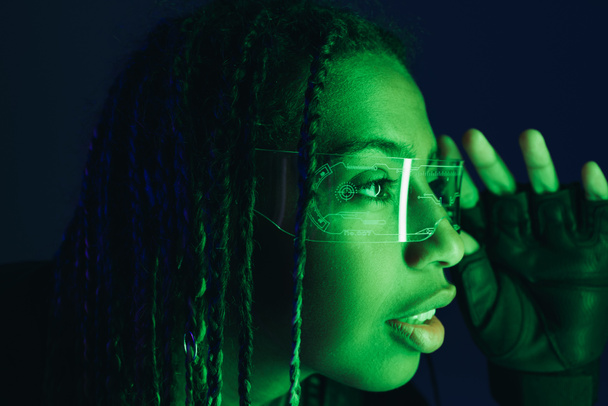 Portrait de femme afro-américaine tenant des lunettes intelligentes isolées sur noir  - Photo, image