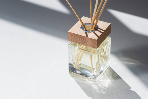 Transparent bottle of aroma diffuser on white background. Eau de parfume for home presentation. Trending concept. Yellow liquid and wooden cap - Fotografie, Obrázek