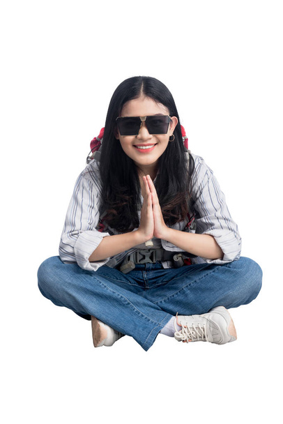 Asian woman with sunglasses and backpack sitting isolated over white background - Zdjęcie, obraz