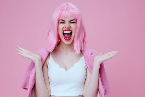 Positif jeune femme en costume rose gesticulant avec ses mains émotions fun fond de couleur inchangée. Photo de haute qualité - Photo, image