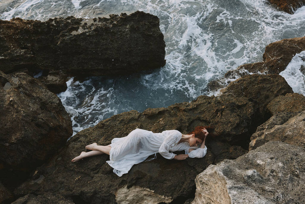 gyönyörű nő feküdt sziklás parton repedések sziklás felületen változatlan. Kiváló minőségű fénykép - Fotó, kép