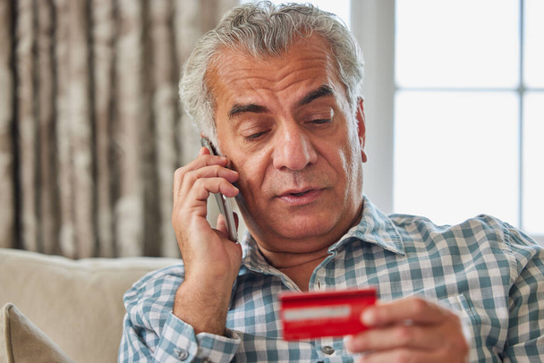 Mature Man At Home Giving Credit Card Details On The Phone - Fotografie, Obrázek