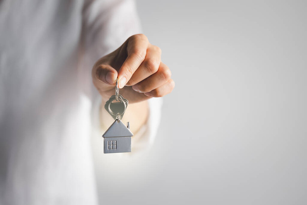 hand holding home key on white background, real estate agent - Zdjęcie, obraz