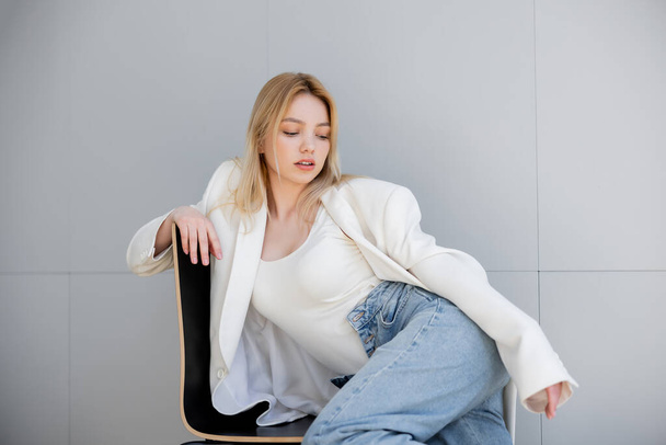 Stylish young woman jacket sitting on chair at home  - Φωτογραφία, εικόνα