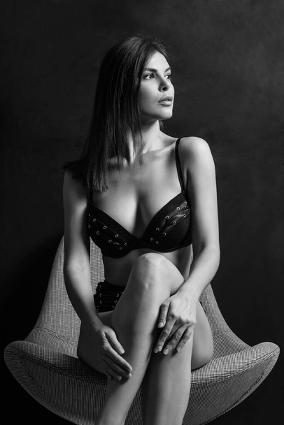 Sexy young woman posing in black underwear over a dark background. - Fotó, kép