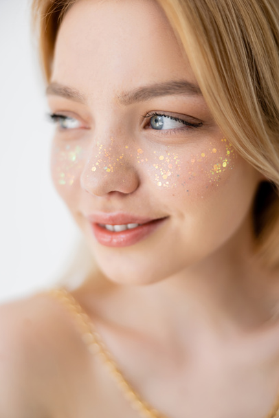 Portrait of young woman with glitter visage looking away isolated on grey  - Photo, Image