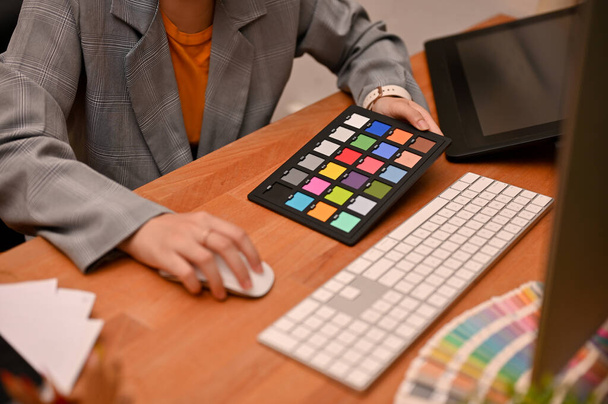 Designer gráfica profissional trabalhando em sua mesa de escritório, usando computador e usando uma placa de xadrez a cores. imagem recortada - Foto, Imagem