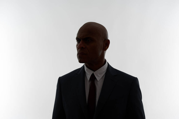 Dark shade of focused adult african american businessman isolated on white background. Adult man wearing suit looking away. Concept of modern successful male lifestyle. Studio shoot. Copy space - Photo, image
