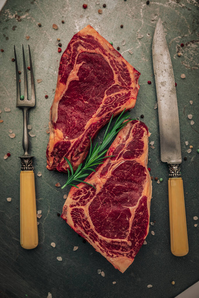 αισθητική διατροφική έννοια του άψητου κόκκινου κρέατος με δεντρολίβανο από πάνω όψη τραπεζιού με τρούφα αλατιού και πιπεριού και μαχαιροπίρουνων - Φωτογραφία, εικόνα