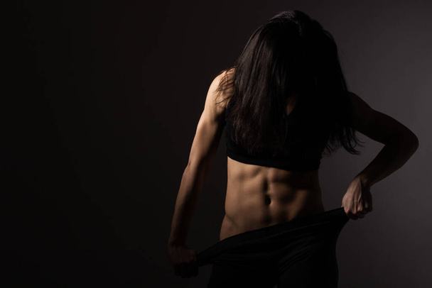 Strong fit woman showing her abs, unrecognizable, dark background - Zdjęcie, obraz