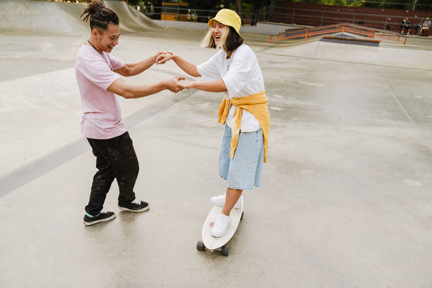 Multiracial friends laughing while riding in skate park on summer day - Foto, imagen