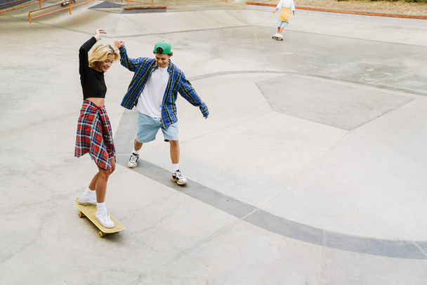 Multiracial friends laughing while riding in skate park on summer day - 写真・画像