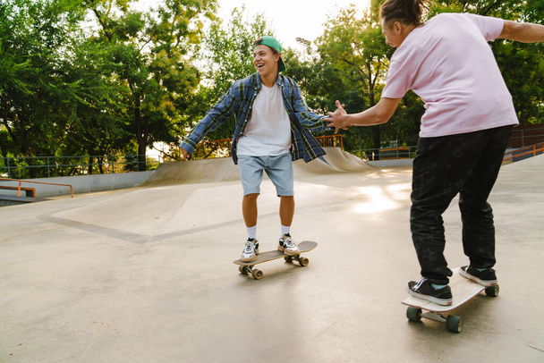 Multiracial friends laughing while riding in skate park on summer day - Valokuva, kuva