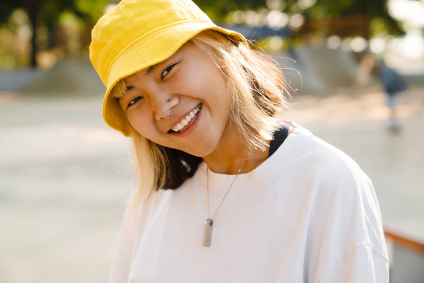 Asian girl wearing hat looking and smiling at camera outdoors - Foto, immagini