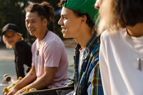 Multiracial teenagers talking and laughing while spending time at skate park outdoors - Fotoğraf, Görsel