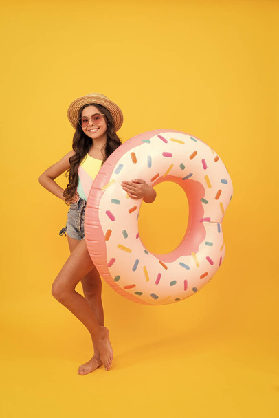 happy girl in straw hat and sunglasses inflatable doughnut ring. child hold beach accessory of inflatable circle swimming ring. active childhood. summertime kid weekend. suntan. summer vacation. - Photo, Image