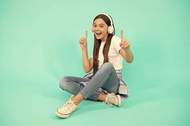 χαρούμενο κορίτσι παιδί ακούει μουσική σε ασύρματα ακουστικά, αξεσουάρ συσκευής. - Φωτογραφία, εικόνα