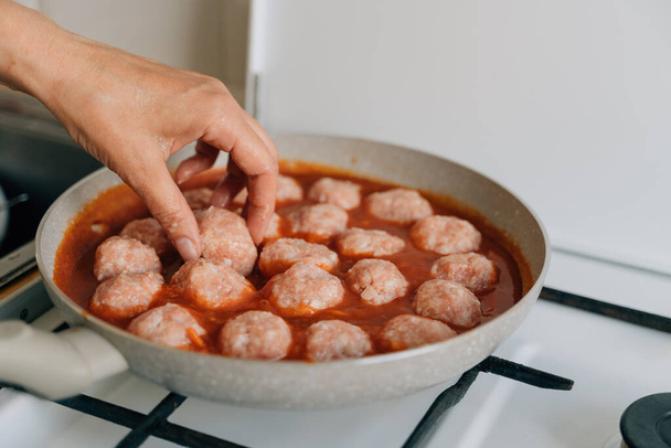 Meatballs cooking process in a pan at home. Beef, chicken and pork meat food recipe in tomato sauce . High quality photo - Foto, Imagen