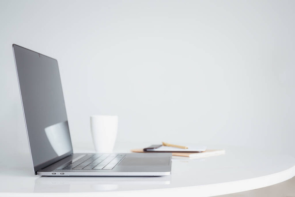 Открыть ноутбук с кофе и ноутбуком на белом столе - Фото, изображение