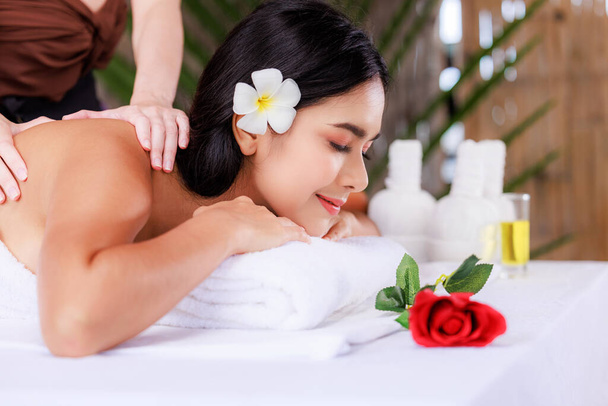 primer plano hermosa joven asiática mujer tumbada relajante en el salón de spa masaje flor rojo en frente, salud y cuerpo cuidado concepto, - Foto, imagen