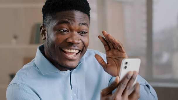 Happy young african american guy businessman handsome entrepreneur man worker hold smartphone talk by video call greeting have virtual meeting chat with friend distance communication remote conference - Fotografie, Obrázek