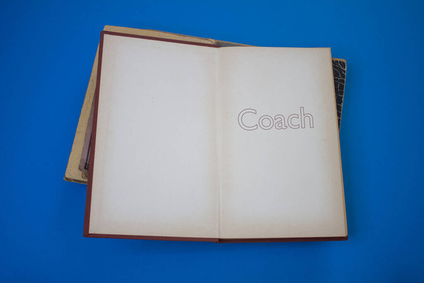 Coach Wort in aufgeschlagenem Buch mit Vintage, natürlichen Mustern altes antikes Papierdesign. - Foto, Bild