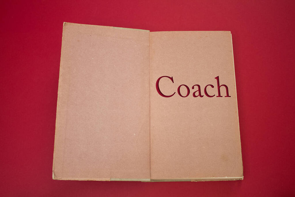 ヴィンテージ、ナチュラルパターンの古いアンティーク紙のデザインで開かれた本の中でコーチの言葉. - 写真・画像