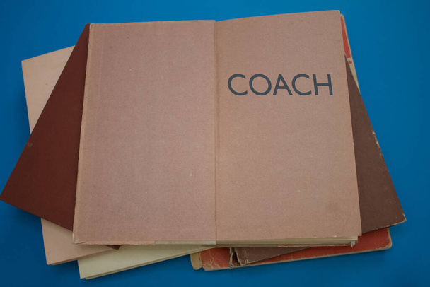 Προπονητής λέξη σε ανοιχτό βιβλίο με vintage, φυσικά μοτίβα παλιά αντίκες σχεδιασμό χαρτιού. - Φωτογραφία, εικόνα
