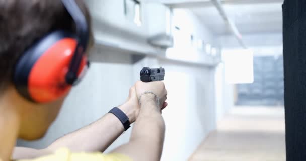 Człowiek celuje pistoletem w cel w pomieszczeniu lub strzelnicy. Trening strzelania pistoletem przez policjantów w koncepcji opon - Materiał filmowy, wideo