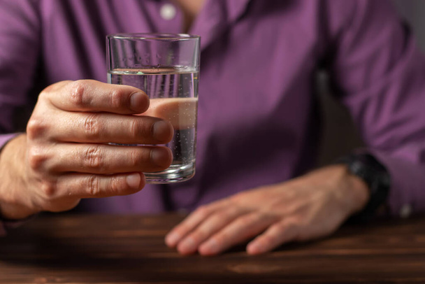 Een man drinkt uit een glas water. Gezondheidszorg concept foto, levensstijl, close up. - Foto, afbeelding