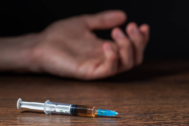 Addict man dead after inject drug overdose with syringe injection heroin to hand. Social disaster and epidemic of narcotic addiction concept - Fotografie, Obrázek
