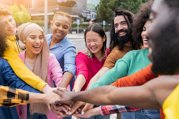 Gruppe junger Freunde im Park treffen sich in der Mitte eines Kreises, um allen Einheit und Stärke zu geben - Millennials in einem Moment der Teambildung - Multirassische Jugend - Foto, Bild
