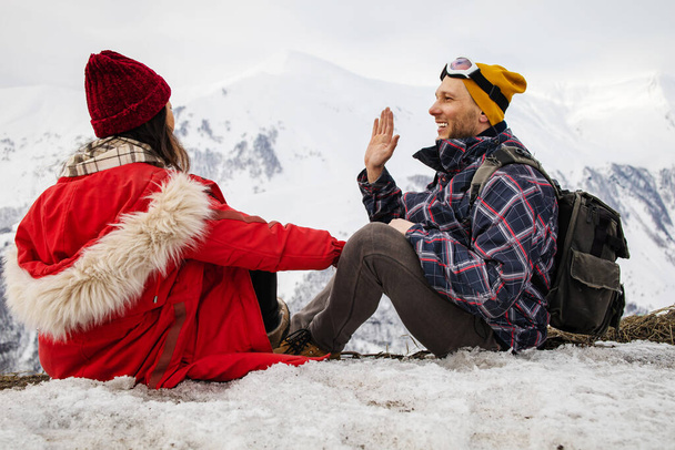 A loving couple plays together in the snow outdoors. Winter holidays in the mountains. Man and woman in knitted clothes have fun on weekends. - Foto, immagini