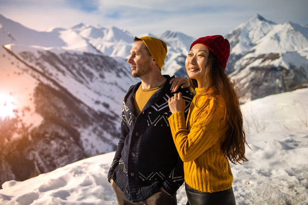 A loving couple plays together in the snow outdoors. Winter holidays in the mountains. Man and woman in knitted clothes have fun on weekends. - Photo, image