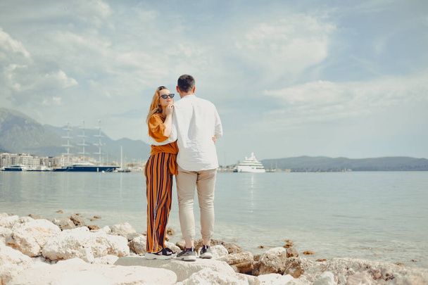 A couple walks along the beach against the backdrop of the sea and mountains. Travel of lovers. Love and honeymoon. Man and girl admiring nature - Fotografie, Obrázek