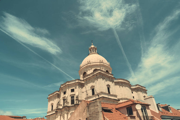Una vista panorámica de la Iglesia de Santa Engracia u otro nombre Panteón Nacional, con un paisaje nublado detrás de ella y algunas casas residenciales en primer plano en un cálido día soleado, Lisboa, Portugal - Foto, imagen